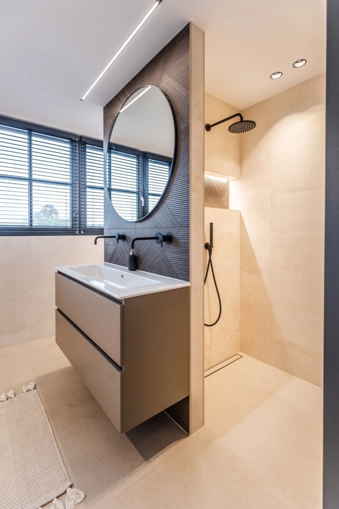 Badkamer met maatwerk scheidingswand en ronde spiegel