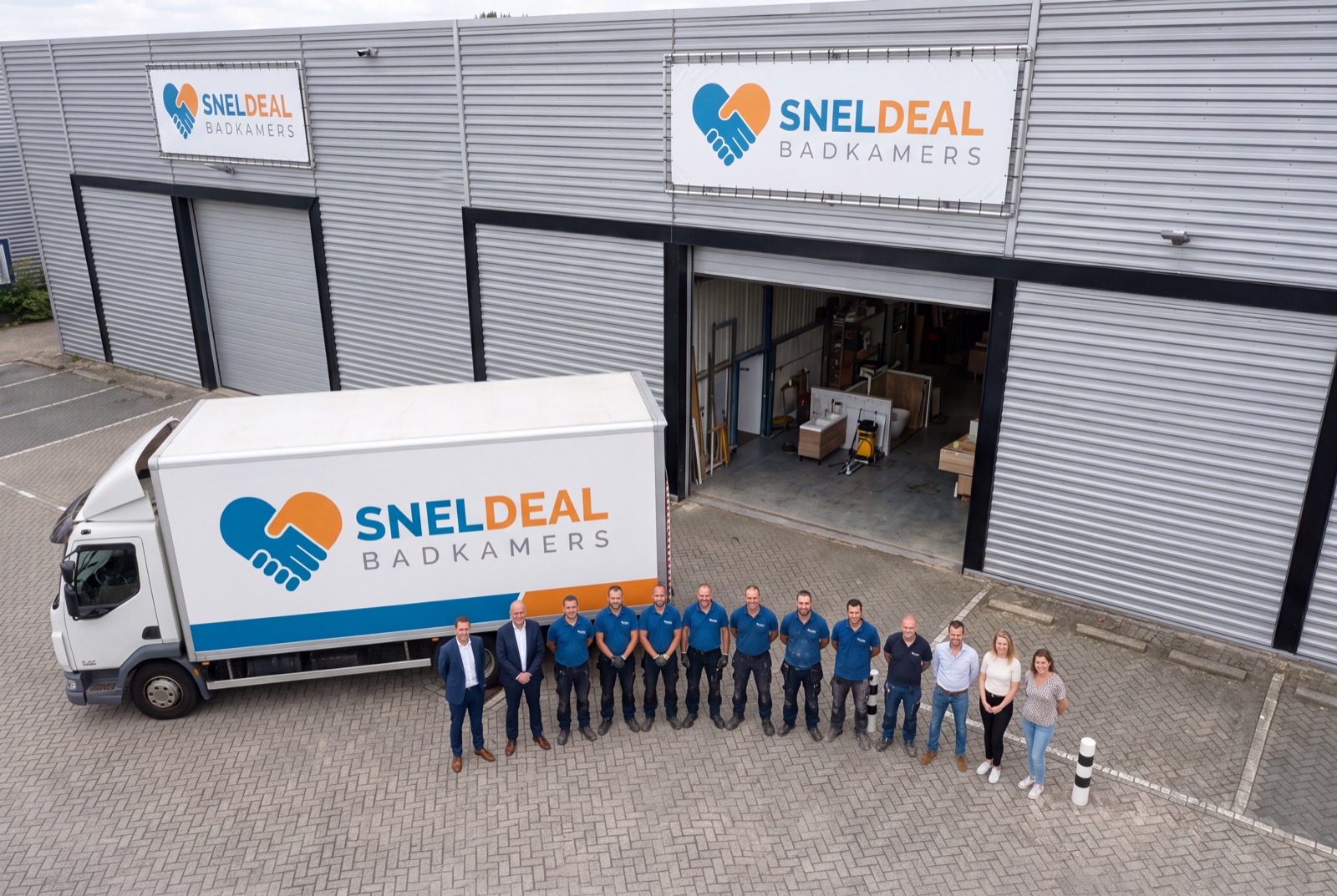 Het team van Sneldeal Badkamers voor de bedrijfshal met de bedrijfsvrachtwagen